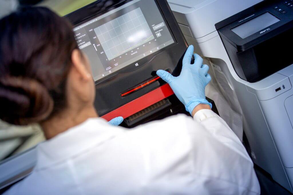 Técnico de laboratorio realizando análisis genéticos en oncología